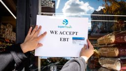 A worker places an Electronic Benefit Transfer sign outside a grocery store in the Bronx borough of New York, on October 24, 2025.