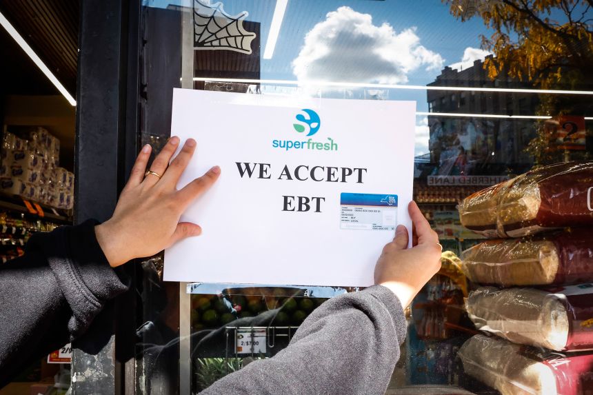 A worker places an Electronic Benefit Transfer sign outside a grocery store in the Bronx borough of New York on October 24, 2025.
