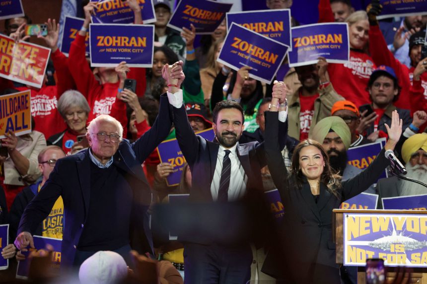 New York City mayoral candidate Zohran Mamdani, center, holds hands with Sen. Bernie Sanders and Rep. Alexandria Ocasio-Cortez at the end of a campaign rally in the Queens borough of New York, on October 26, 2025.