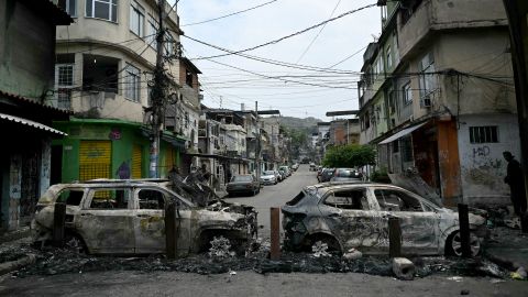 A man stands next to cars burnt during a barricade within the Operacao Contencao (Operation Containment) at the Vila Cruzeiro favela, in the Penha complex, in Rio de Janeiro, Brazil, on October 28, 2025. At least 2,500 agents took part in an operation to arrest drug traffickers from the Comando Vermelho (CV), which resulted in, at least, 18 suspects and several police officers dead. (Photo by Mauro PIMENTEL / AFP) (Photo by MAURO PIMENTEL/AFP via Getty Images)