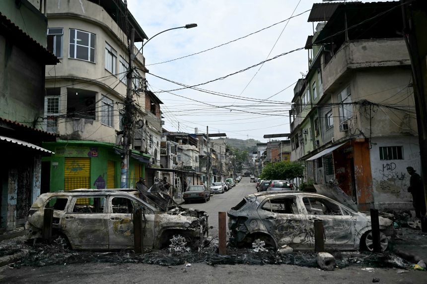 A man stands next to a burnt out car at a barricade in Rio's Compresso da Peña on October 28.