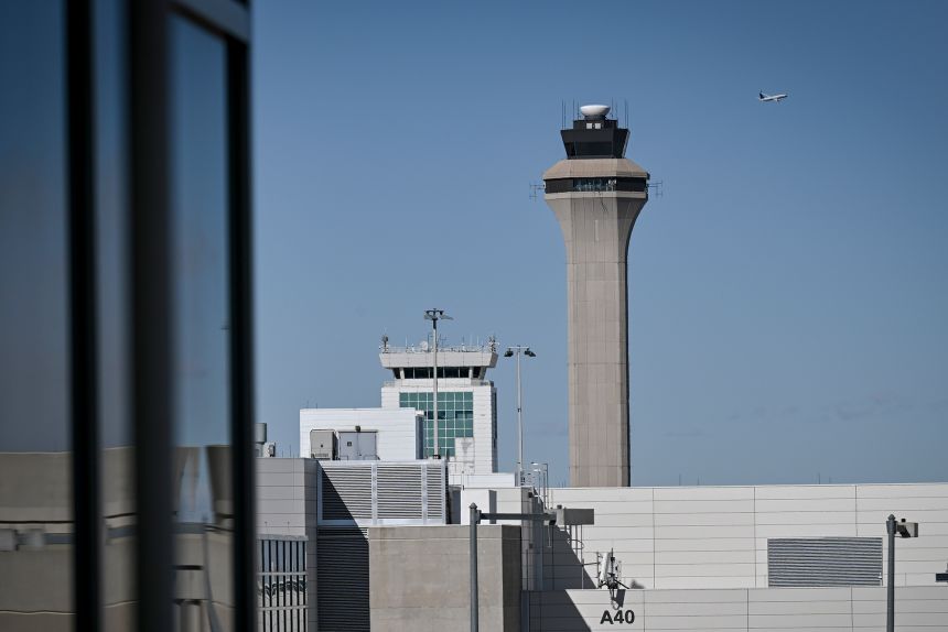 A plane takes off near the control tower at Denver International Airport. Some air traffic controllers complain of poor health, while others choose to retire.