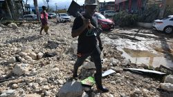 A man walks with a shovel in hand over rubble on Main Street in Santa Cruz, St. Elizabeth, Jamaica on October 29, 2025. Hurricane Melissa ripped up trees and knocked out power after making landfall in Jamaica on October 28, 2025 as one of the most powerful hurricanes on record, inundating the island nation with rains that threaten flash floods and landslides. (Photo by Ricardo MAKYN / AFP) (Photo by RICARDO MAKYN/AFP via Getty Images)          