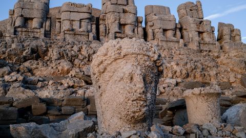 A weathered stone head stands among fallen fragments beneath the seated statues of Mount Nemrut in Adiyaman, Turkey on October 29, 2025. The UNESCO-listed archaeological site, built by the Kingdom of Commagene at 2,206 meters, continues to draw tourists who photograph its colossal sculptures and mountainous landscape. (Photo by Bilal Seckin / Middle East Images via AFP) (Photo by BILAL SECKIN/Middle East Images/AFP via Getty Images)          