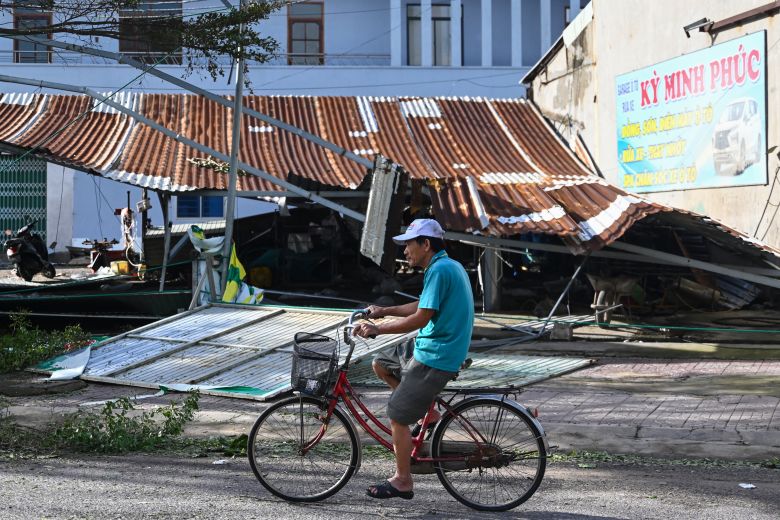 A man cycles past a partially collapsed roof structure in the Quy Nhon coastal area of Gia Lai province, central Vietnam on November 7, 2025.