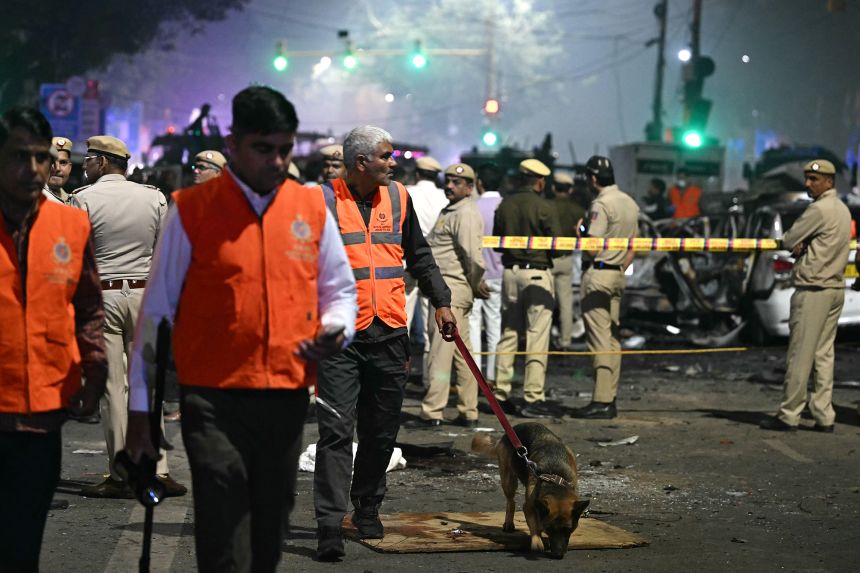 Police lead a sniffer dog at the blast site on Monday.