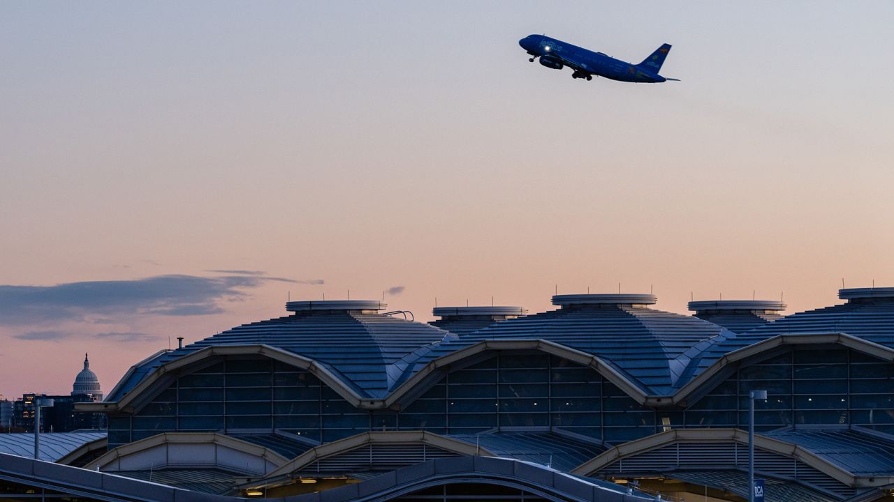 A JetBlue plane takes off from Ronald Reagan Washington National Airport (DCA) in Arlington, Virginia, US, on Tuesday, Nov. 11, 2025. The havoc plaguing the US travel industry will likely escalate Tuesday when tighter federal restrictions on flights take effect, even while lawmakers move closer toward ending the government shutdown. Photographer: Eric Lee/Bloomberg via Getty Images