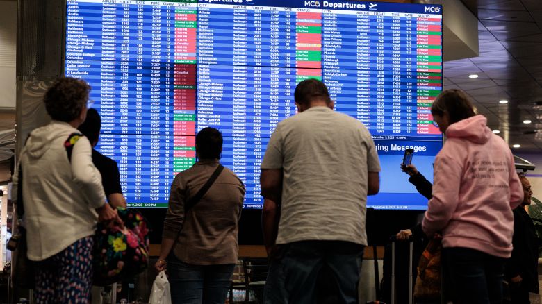 Passengers look at flight delays on a departure board at Orlando International Airport before the government reopened.