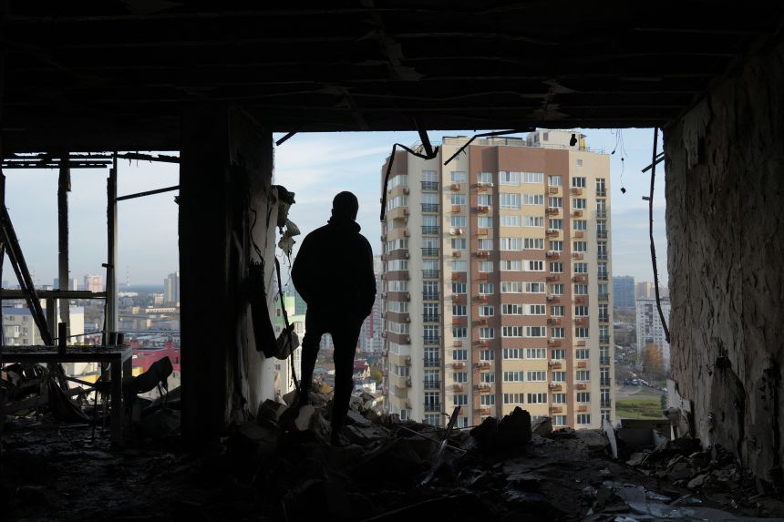 A person stands in a destroyed apartment in a damaged residential building following an air strike in Kyiv on November 14, 2025