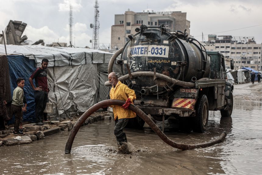 A Palestinian man clears standing water from a road near a camp for displaced people after the first winter rains in Gaza City on Friday.