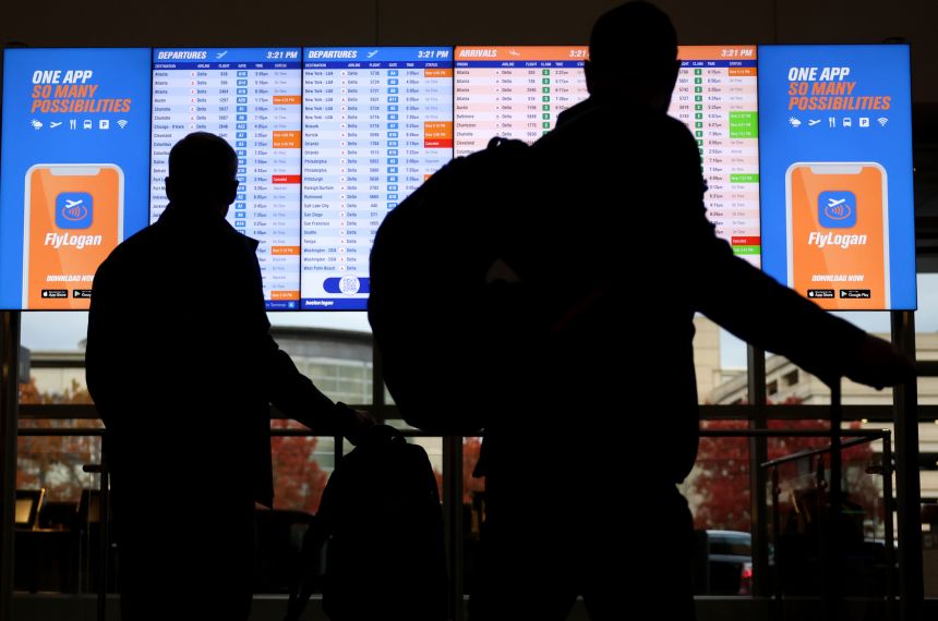 Passengers stop to look at the arrivals and departures board at Logan Airport, on November 11.