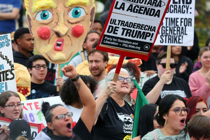 Protesters yell and hold signs Saturday, November 15, during the No Border Patrol protest in uptown Charlotte.