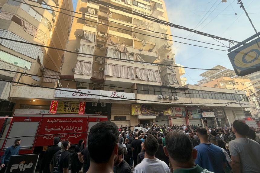 People gather looking at a residential building following an Israeli military strike in Beirut's southern suburbs.
