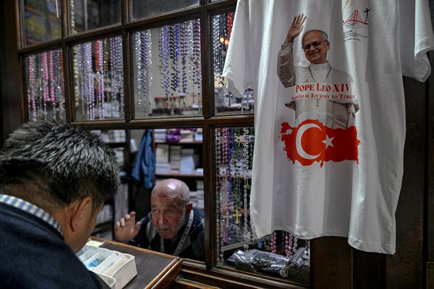 Candles and religious books are on sale as a t-shirt bearing a portrait of Pope Leo XIV and a Turkish flag is displayed ahead of Pope's visit in Istanbul on Monday.
