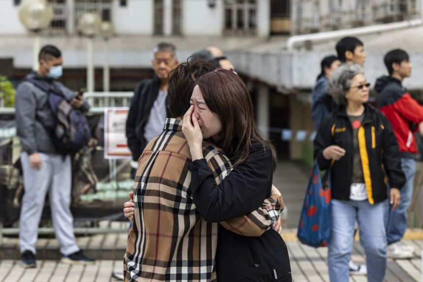 A woman is seen crying near residential buildings that continue to burn at Wang Fuk Court in Tai Po, Hong Kong on November 27, 2025.