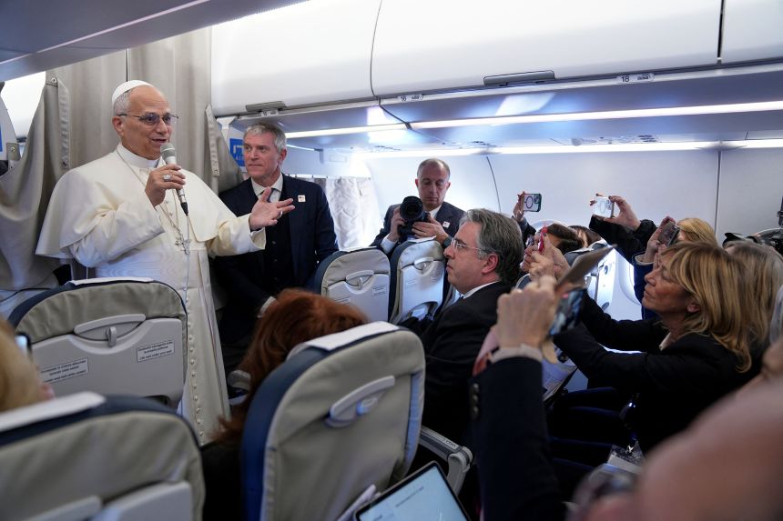 Pope Leo XIV greets reporters aboard a flight on his way to Ankara.