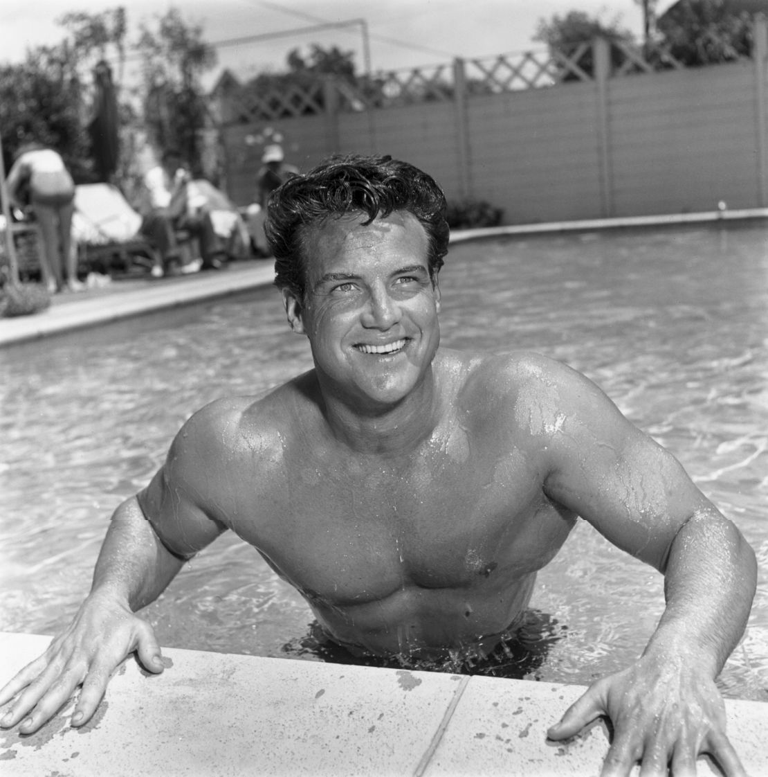 12 de junio de 1952: El culturista y ganador de un título de Mr. América y dos de Mr. Universo, Steve Reeves (1926 - 2000), sonríe al borde de una piscina.