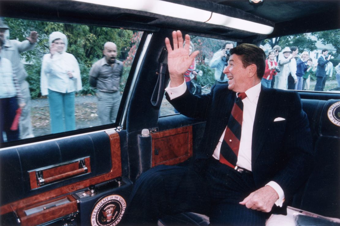 President Ronald Reagan waves from the back of his limousine to a line of people on the street as he heads toward a campaign stop in Fairfield, Connecticut, on October 26, 1984.