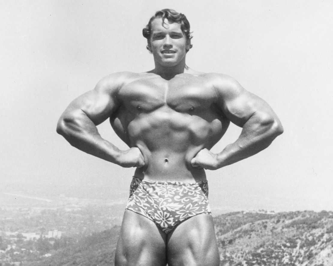 1966: Imagen de Arnold Schwarzenegger de pie y flexionándose en la cima de una colina cerca de Muscle Beach, Santa Mónica, California.