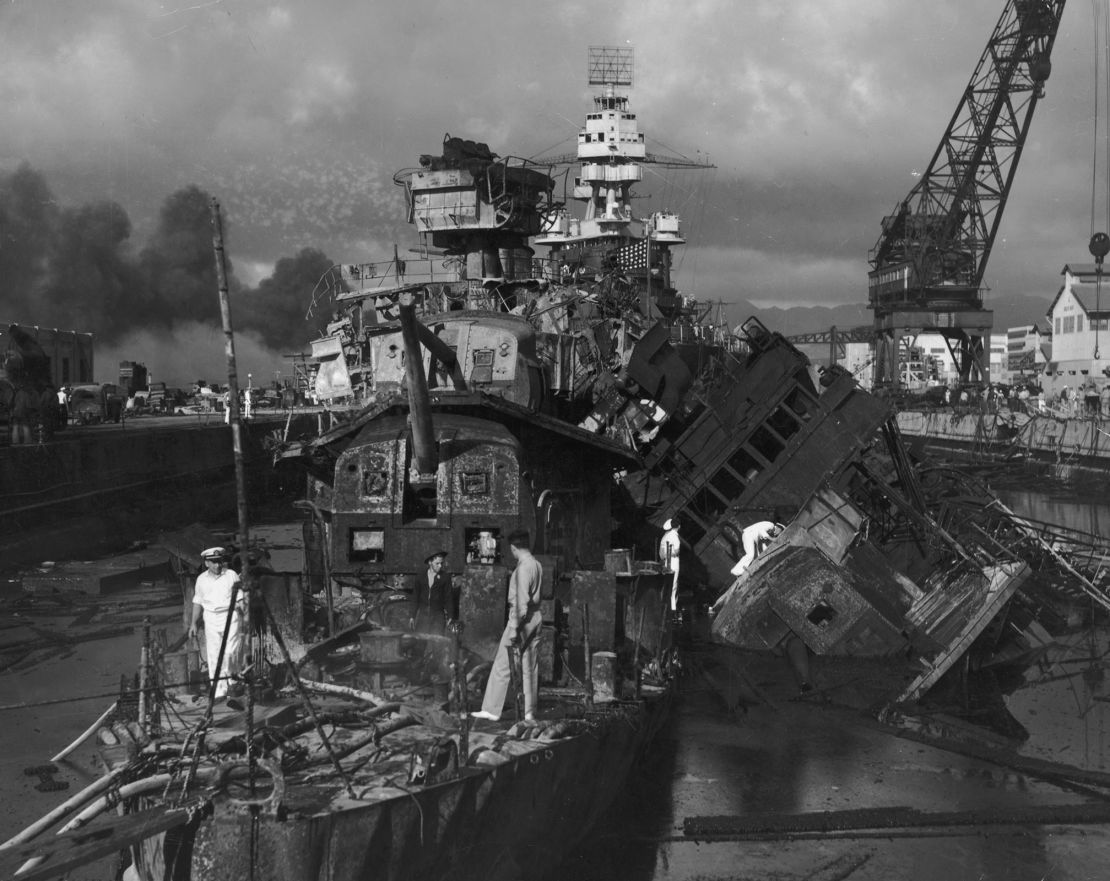 Sailors walk amongst the wreckage of the American destroyers USS Cassin and USS Downes after the Japanese attack on Pearl Harbor, Hawaii, on December 7, 1941. The battleship USS Pennsylvania is visible in the background.