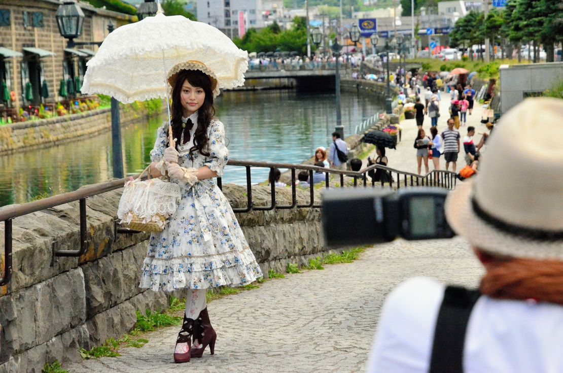 A young woman sporting Lolita fashion poses for photographs along the Otaru Canal in the background on June 29, 2014 in Otaru, Hokkaido, Japan. About 90 girls and young women decked out in lacy Lolita fashions participated in a photo session and tea party event in the port city.
