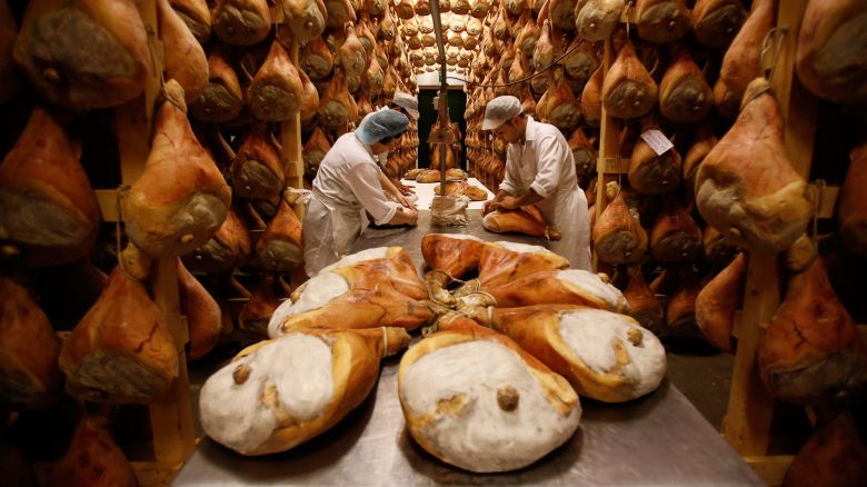 Employees grease hams with lard before hanging them to dry in storage as part of the Parma ham curing process at Pio Tosini Industria Prosciutti SpA in Langhirano, Italy, on Thursday, Sept. 25, 2014. Russia recently announced a one-year ban on a range of food products from the EU and the U.S., in retaliation for sanctions against the country over Ukraine. Photographer: Alessia Pierdomenico/Bloomberg via Getty Images