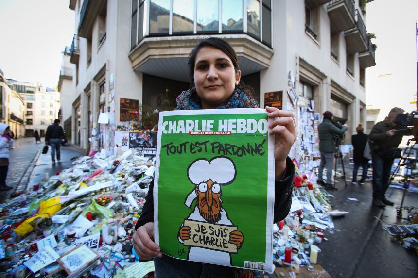 A woman poses with her copy of the French satirical magazine 'Charlie Hebdo' in front of the 'Rue Nicolas Appert' on January 14, 2015 in Paris, France.