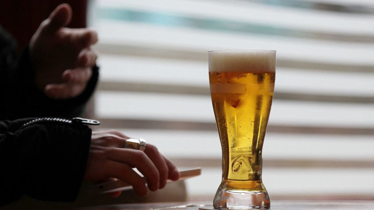 A man holds his smartphone next to a glass of beer as he sits at a bar table on March 10, 2015 in Pont-Audemer, northwestern France. AFP PHOTO/CHARLY TRIBALLEAU. (Photo by CHARLY TRIBALLEAU / AFP) (Photo by CHARLY TRIBALLEAU/AFP via Getty Images)