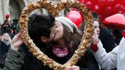 Una pareja se besa mientras posa detrás de un pastelito en forma de corazón durante un flashmob en París el 14 de febrero de 2014.
