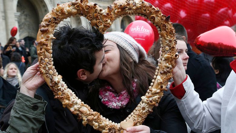 Una pareja se besa mientras posa detrás de un pastelito en forma de corazón durante un flashmob en París el 14 de febrero de 2014.