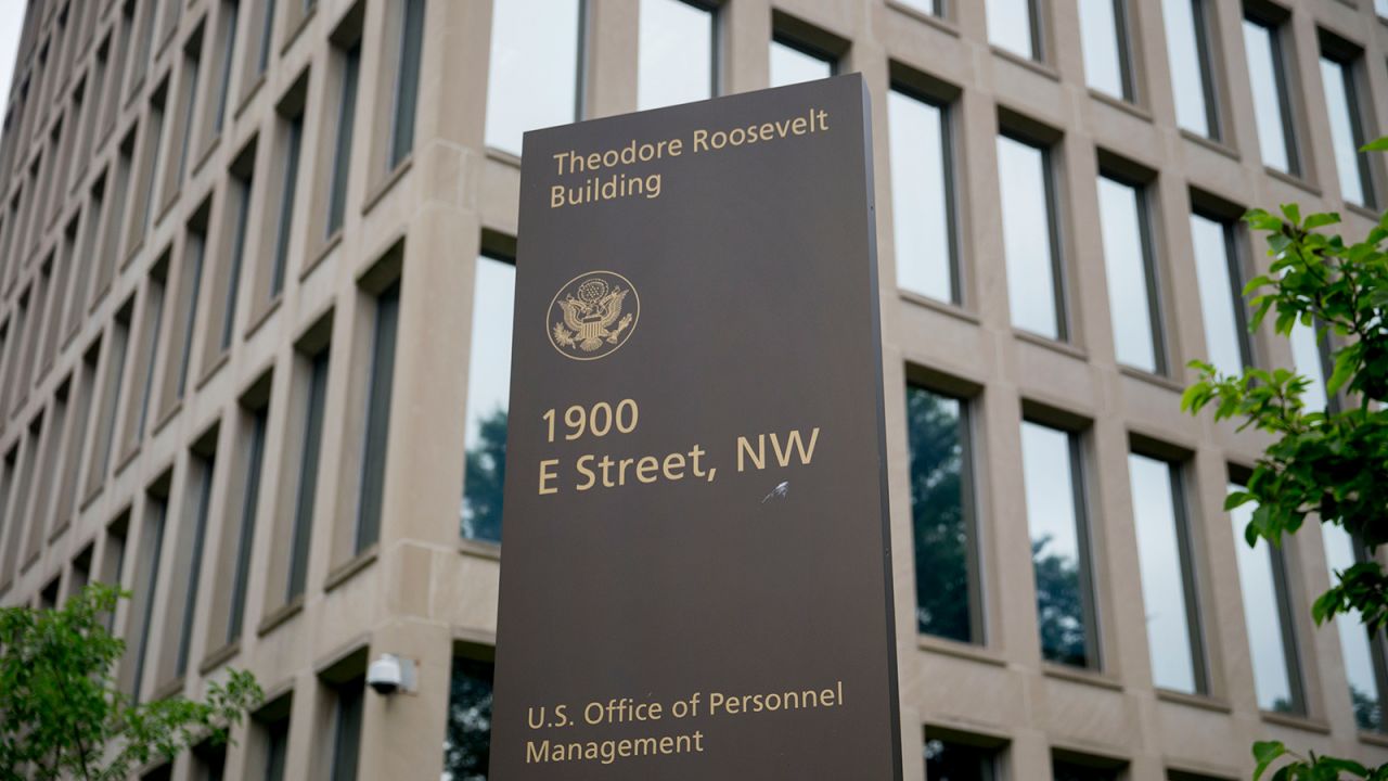 A sign stands outside of the Theodore Roosevelt Building, headquarters of the U.S. Office of Personnel Management (OPM), in Washington, D.C., U.S., on Friday, June 5, 2015.