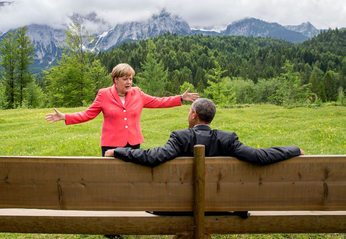 TOPSHOT - Germany's Chancellor Angela Merkel (L) gestures while chatting with US President Barack Obama sitting on a bench outside the Elmau Castle after a working session of a G7 summit near Garmisch-Partenkirchen, southern Germany, on June 8, 2015. AFP PHOTO / POOL / MICHAEL KAPPELER (Photo by MICHAEL KAPPELER / POOL / AFP) (Photo by MICHAEL KAPPELER/AFP via Getty Images)