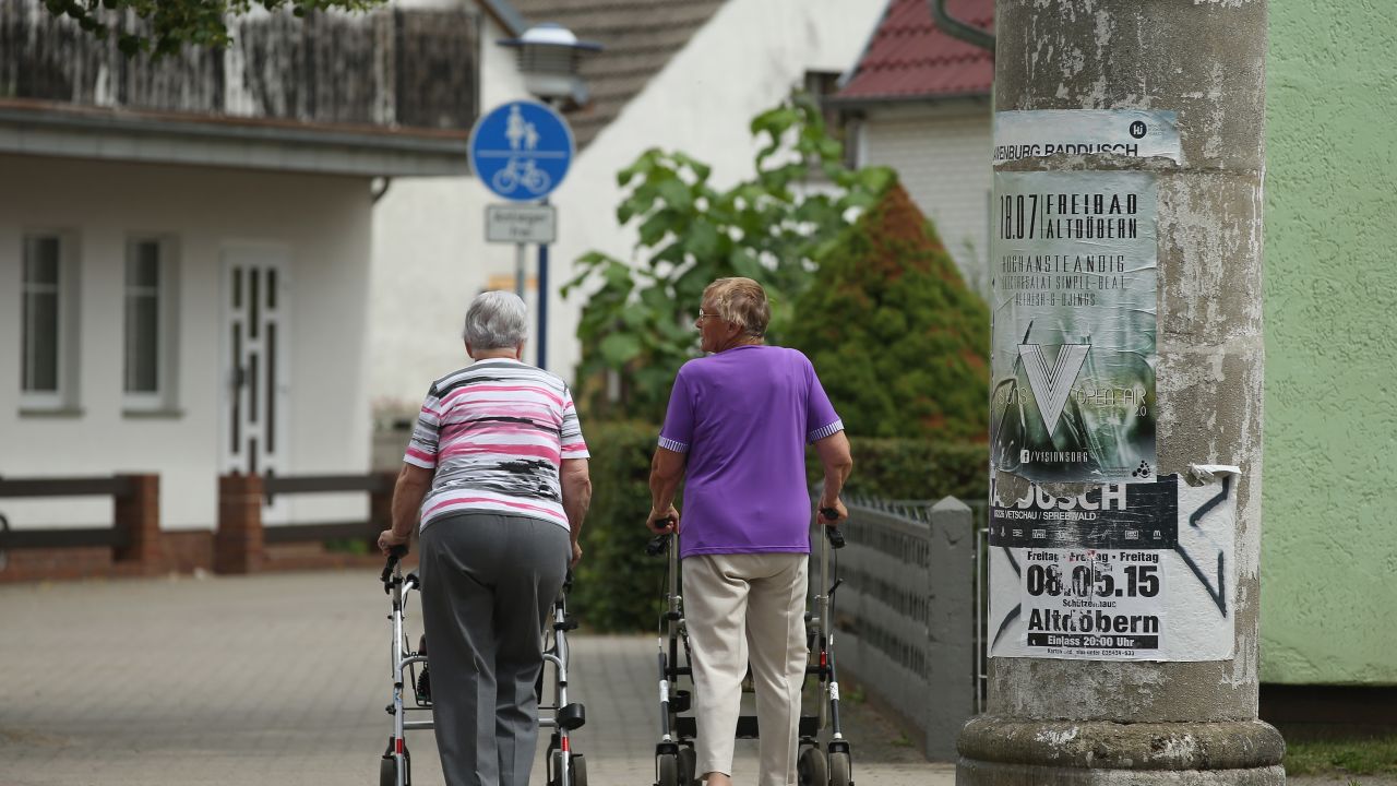 ALTDOEBERN, GERMANY - JULY 15:  Two elderly women walk along a street on July 15, 2015 in Altdoebern, Germany. Altdoebern is located in a region where open-pit coal mines once abounded and that over the last two decades has experienced among the sharpest population drops in Germany. In 1964 the city counted 4,694 inhabitants, in 2012 only 2,605, which has led to the closing of schools and a severe shrinking of the economy. Before the communist government of East Germany collapsed in 1989 open-pit coal mines were a vital source of employment in the region and their decline has pulled the local economy down with them. 25 years since German reunification eastern Germany is struggling with a low birth rate, rural emigration and unemployment rates higher than in western Germany.  (Photo by Sean Gallup/Getty Images)