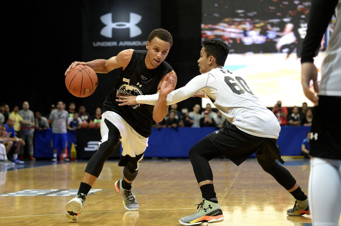 NBA Golden State Warriors and a two-time Most Valuable Player (MVP) Stephen Curry (left) drives the ball during a drill with young players in Manila on September 5, 2015 while wearing Under Armour's limited edition basketball shoes, 