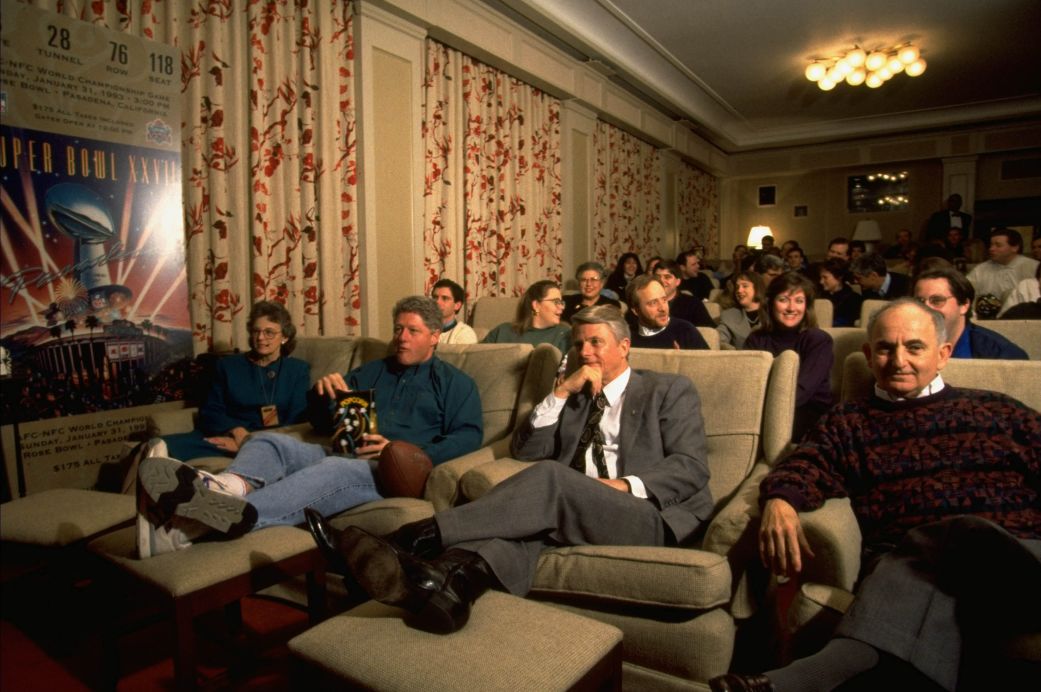 President Bill Clinton (center left) watching Super Bowl in the family theater with governor guests and White House staffers in 1994.