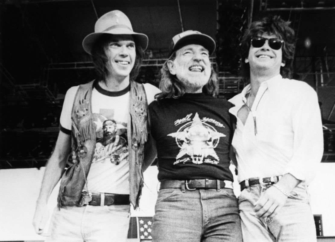 Singer-songwriters Neil Young, Willie Nelson, and John Mellencamp stand together on stage during the 1985 Farm Aid.