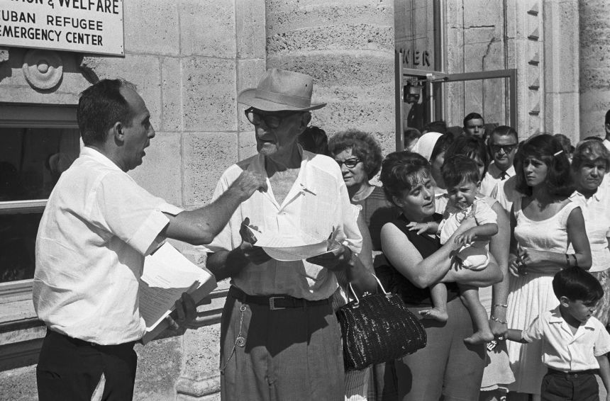 A Cuban refugee worker hands out forms to waiting Cubans at the Cuban Refugee Emergency Center in 1965. The forms are asking for information concerning those relatives still on the Island of Cuba. Refugees here are hopeful of getting their relatives out of Cuba since Castro's offer to let them go.