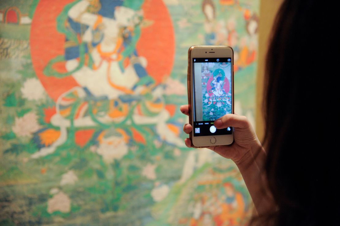 A guest takes a photo of Buddhist artwork during the 2016 Asia Week Celebration at Rubin Museum of Art on March 17, 2016.