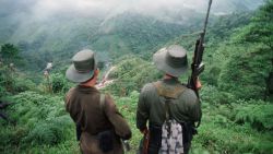 FLORENCIA, COLOMBIA:  Two armed soldiers belonging to the Revolutionry Armed Forces of Colombia (FARC) monitor the Berlin pass, 07 March, near Florencia, in the  southern Caqueta province of Colombia, where cars are prevented from going through after the rebels decreed 06 March a ban on "travel on roads and waterways for six days". The rebels try to dissuade voters from casting their ballots in the 08 March elections for congress. According to the rebels, the elections 08 March are illegitimate because the left has been forced out of national politics, following the murder over the past years of thousands of Colombia's left-wing politicians and supporters. AFP PHOTO PEDRO UGARTE (Photo credit should read PEDRO UGARTE/AFP via Getty Images)