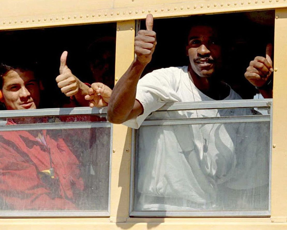 Refugiados cubanos saludan desde un autobús que los lleva a sus nuevos campamentos en la base naval estadounidense en la Bahía de Guantánamo, Cuba, el 1 de febrero de 1995.