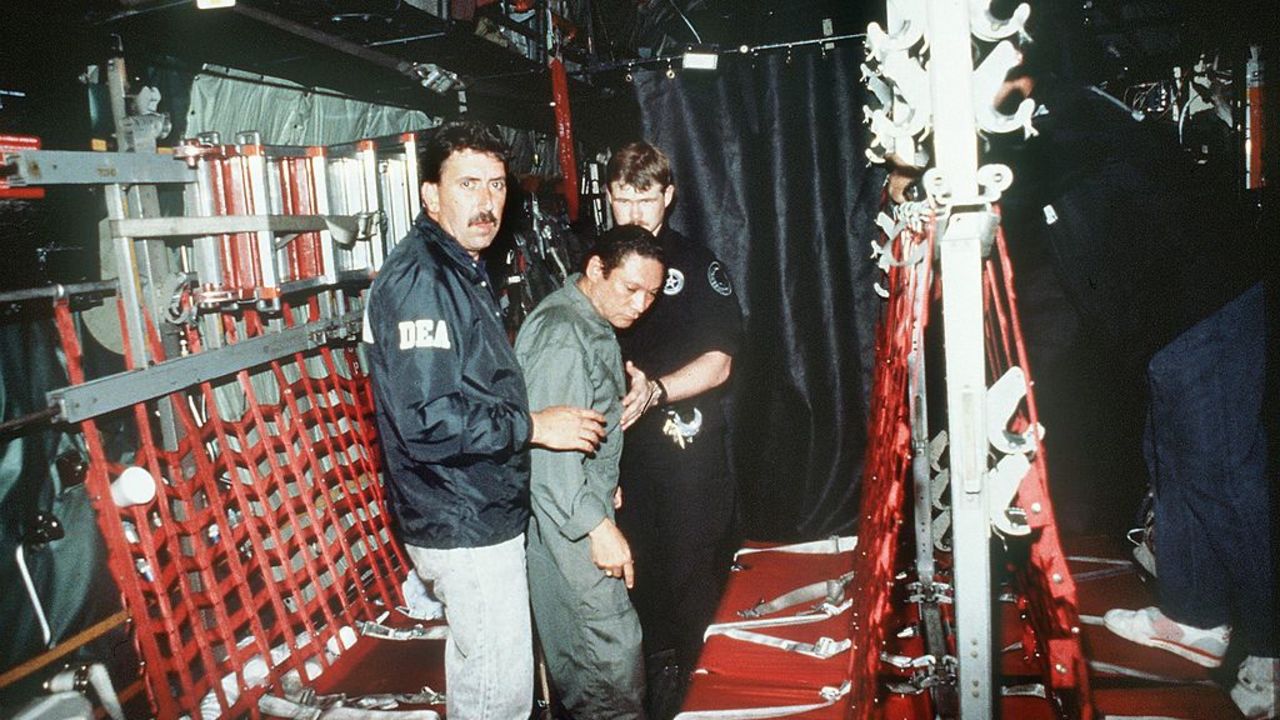HOWARD AIR FORCE BASE,- JANUARY3: In this photo released 04 January 1990 by the Defense Department, Panamian General Manuel Noriega (C) is brought on board a US military plane 3 January 1990 for a flight to Miami after his arrest. (Photo credit should read STF/AFP via Getty Images)