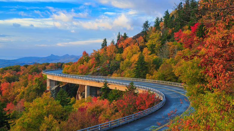 Linn Cove Viaduct on the Blue Ridge parkway in the fall season. Road winding through the mountains with autumn colors and blue vibrant morning skies.