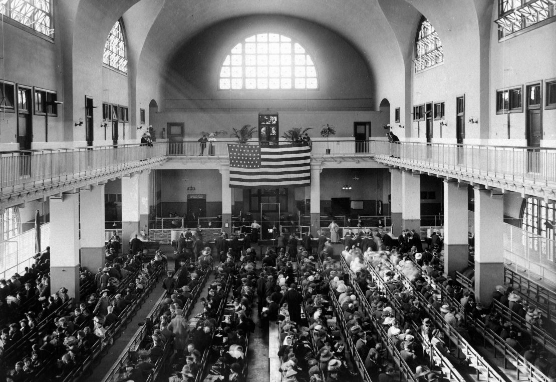 This 1907 photo shows the main hall of the United Station immigration inspection station on Ellis Island, where new immigrants lined the benches as they awaited processing and an American flag hung from the second floor.