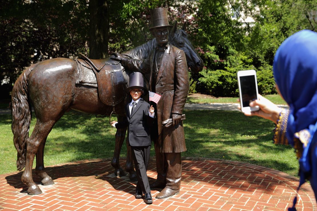 Yahya Ahmed Aflal, 6, has his photograph taken with a statue of President Abraham Lincoln following a citizenship ceremony at President Lincoln's Cottage in May 2016.