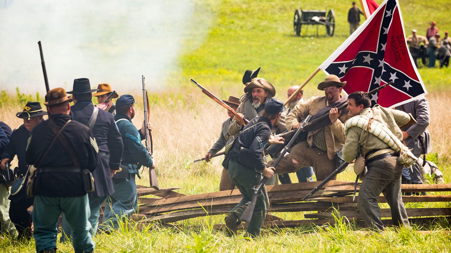 Confederate reenactors breach a Union barricade during a staging of Battle of Gettysburg.