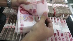 BEIJING - JULY 22: (CHINA OUT) A clerk counts stacks of Chinese yuan at a bank on July 22, 2005 in Beijing, China. The People's Bank of China, the central bank, announced on July 21 to scrap the yuan's decade-old peg to the U.S. dollar, and in stead phase in a flexible mechanism of the yuan exchange rates. The exchange rate of yuan vs U.S. dollar was announced at 8.11 vs 1 on July 22. (Photo by China Photos/Getty Images)