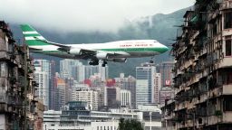 Hong Kong flag carrier Cathay Pacific, Boeing 747-400 jumbo jet, flies over the Kai Tak Airport control tower bottom as it approaches the Runway 13 on the last day of the 73-year-old airport 05 July. The cramped saturated urban airport will be replaced Monday, 06 July, by a massive, shiny state-of-the-art version on an outlying island with purpose-built transport links. (Photo by Manny CENETA / AFP) (Photo by MANNY CENETA/AFP via Getty Images)