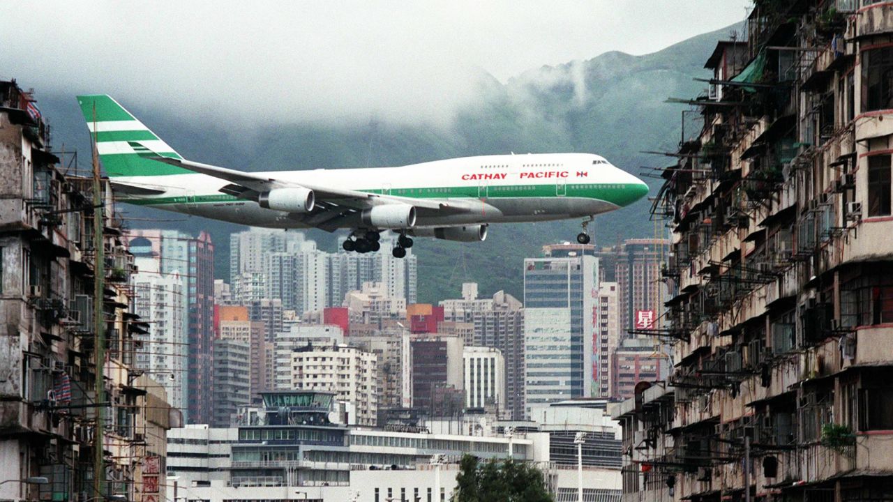 Hong Kong flag carrier Cathay Pacific, Boeing 747-400 jumbo jet, flies over the Kai Tak Airport control tower bottom as it approaches the Runway 13 on the last day of the 73-year-old airport 05 July. The cramped saturated urban airport will be replaced Monday, 06 July, by a massive, shiny state-of-the-art version on an outlying island with purpose-built transport links. (Photo by Manny CENETA / AFP) (Photo by MANNY CENETA/AFP via Getty Images)