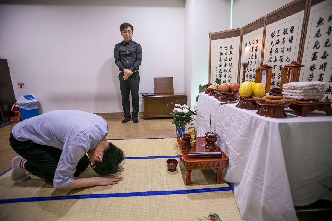 A volunteer for Good Nanum bows at a makeshift shrine for two deceased, who died lonely at home and hospitals, inside a waiting room of a crematorium on July 4, 2016 in Goyang, South Korea.