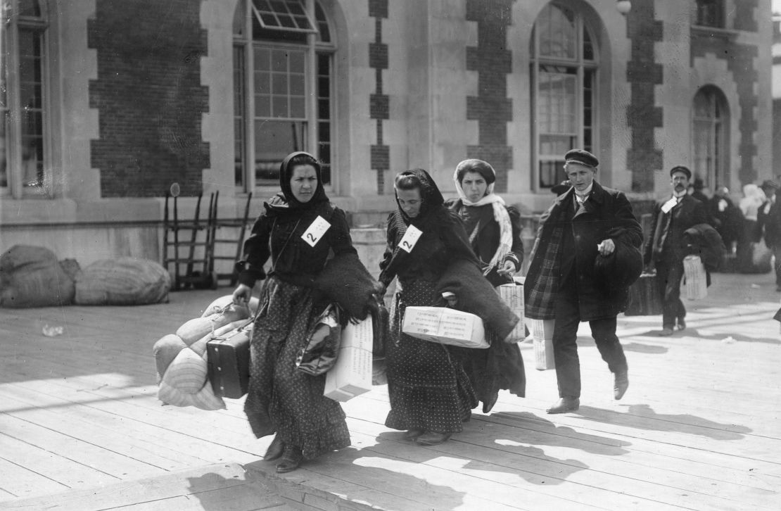 A group of recently arrived immigrants carry their belongings on Ellis Island in the early 1900s.